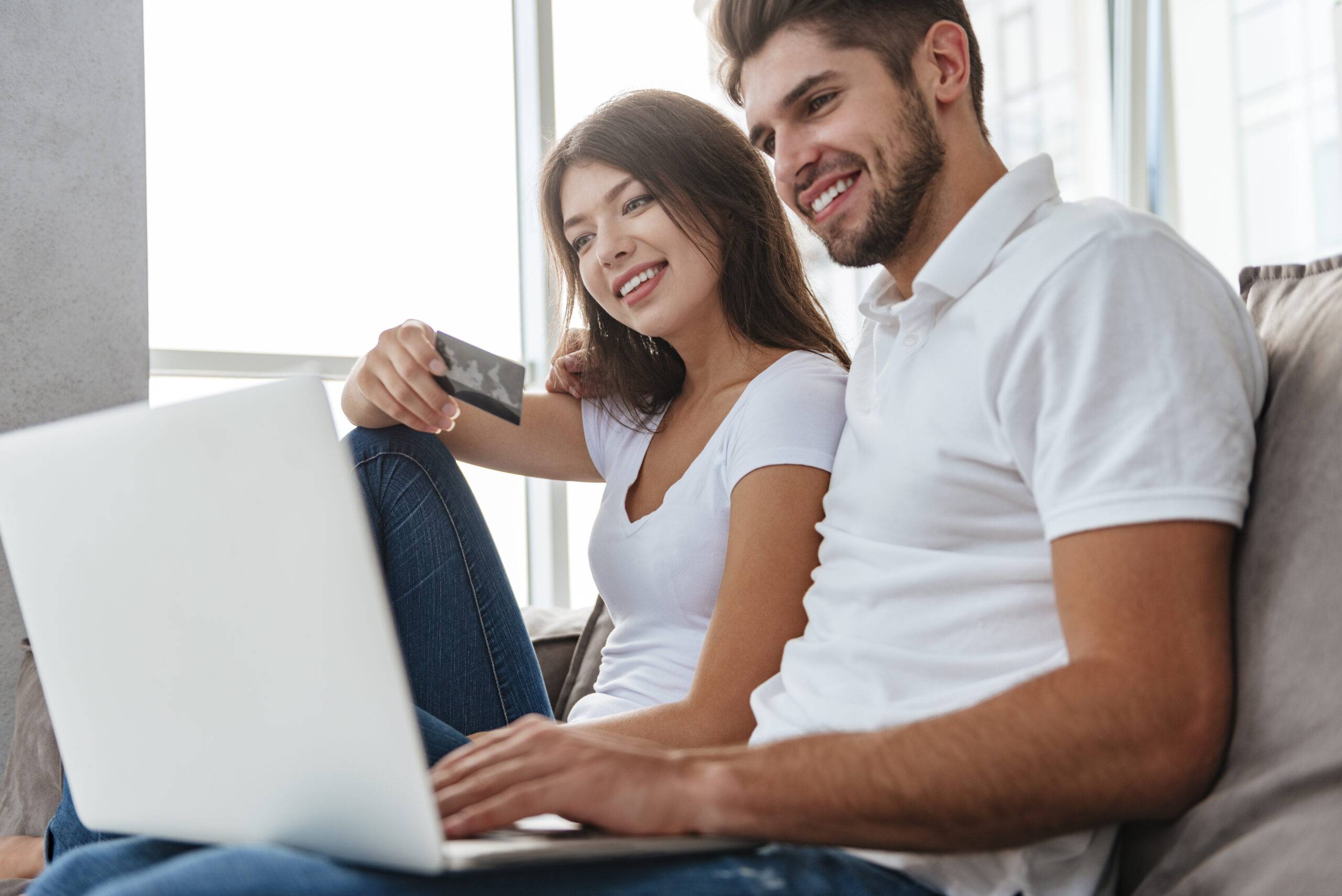 Happy young couple sitting and doing online shopping at home